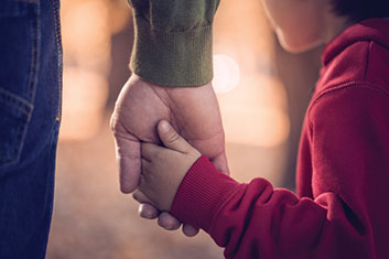 A parent and child holding hands. Links to Gifts by Estate Note